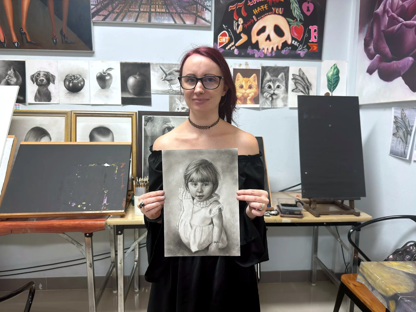 Adult student holding a detailed black and white portrait drawing
