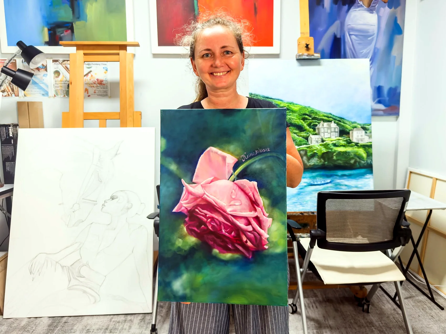 Adult learner holding a finished rose painting