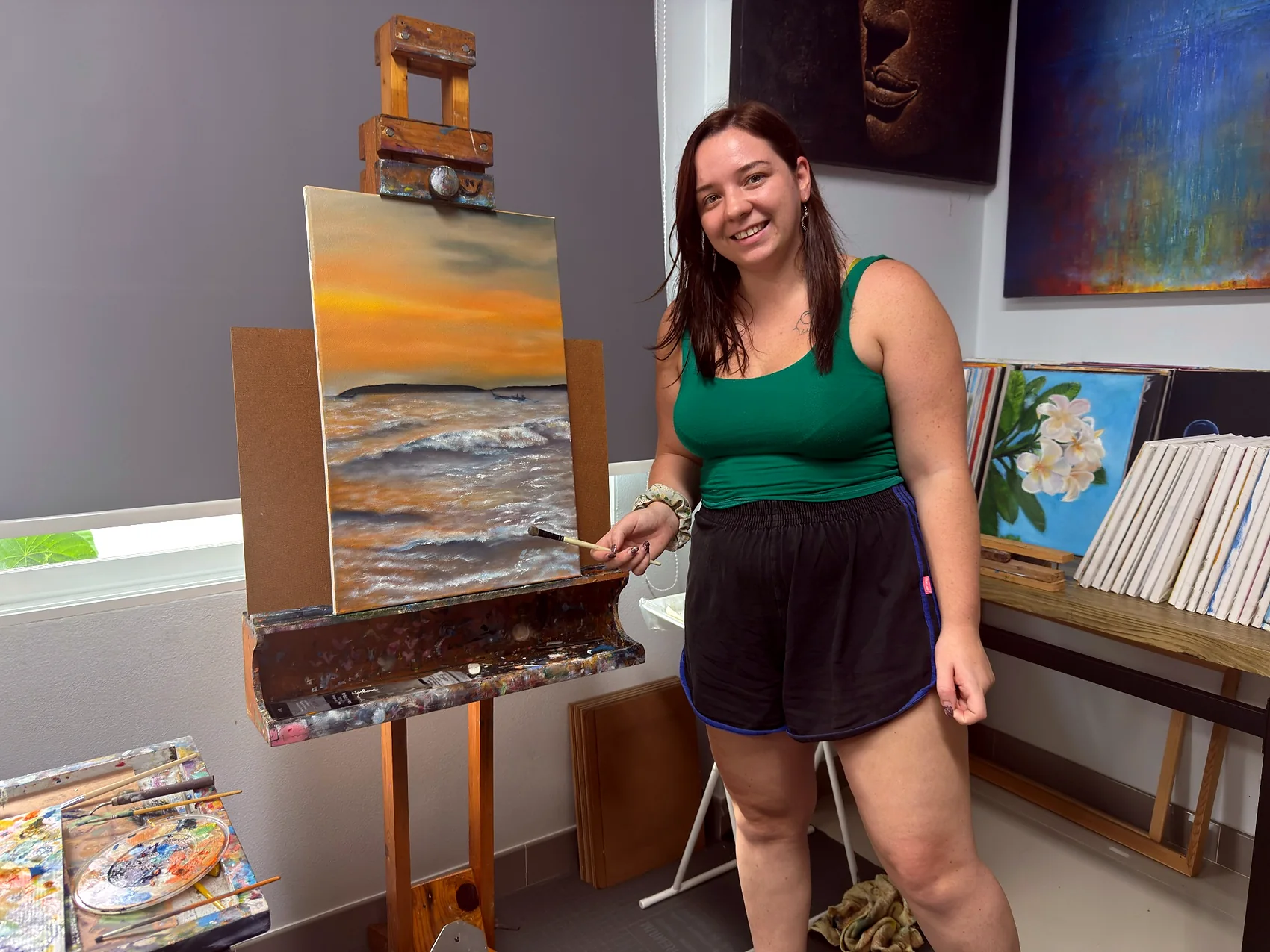 Adult learner beside a sunset seascape painting