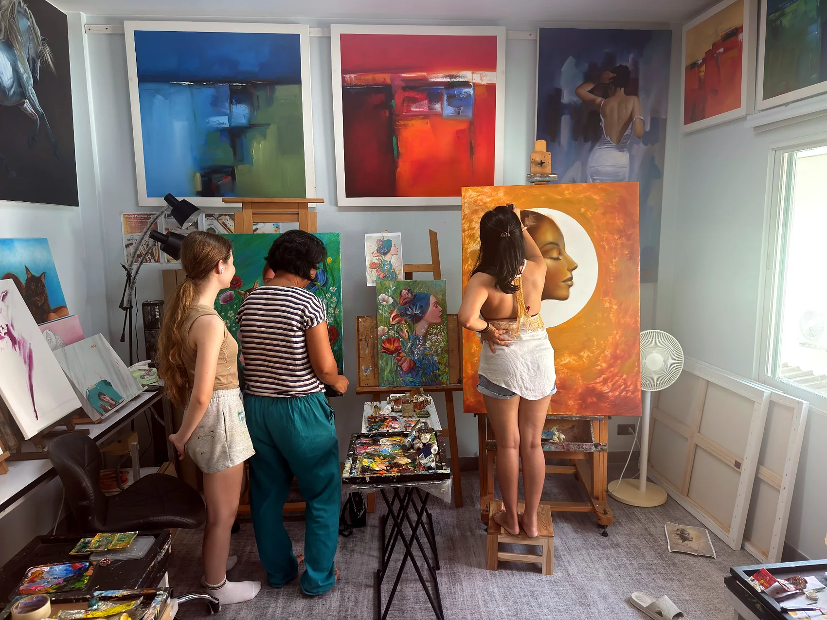 Artists working on large paintings inside the studio
